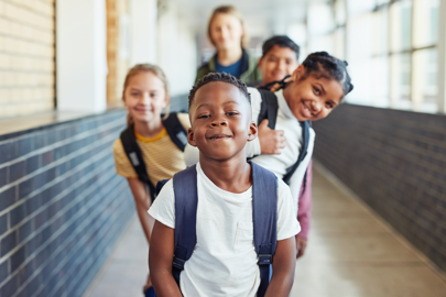 image of five young children with backpacks on