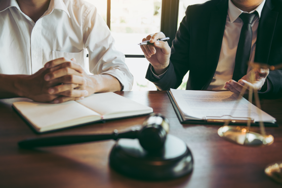 image of two people sitting at table reviewing documents, with gavel in foreground