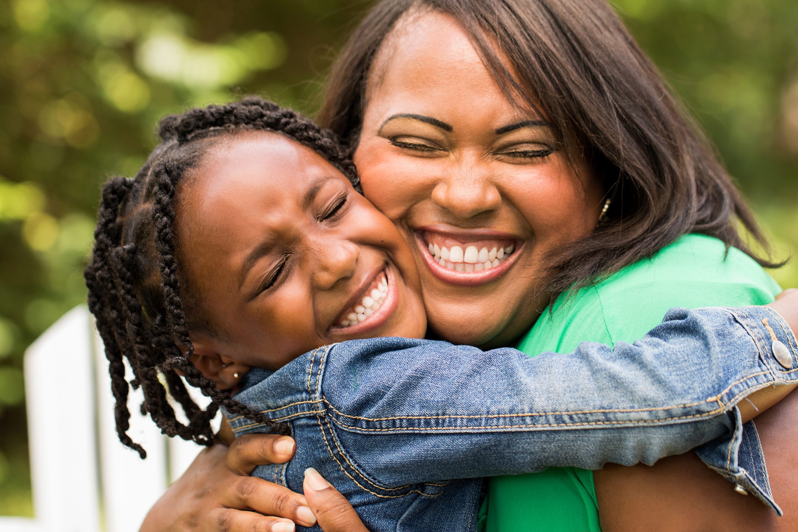 image of woman hugging young girl tightly, both smiling