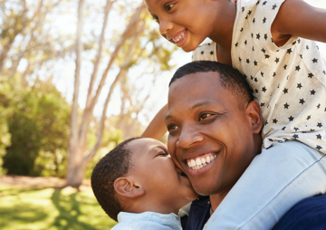 image of man with young boy and young girl on shoulders, all smiling