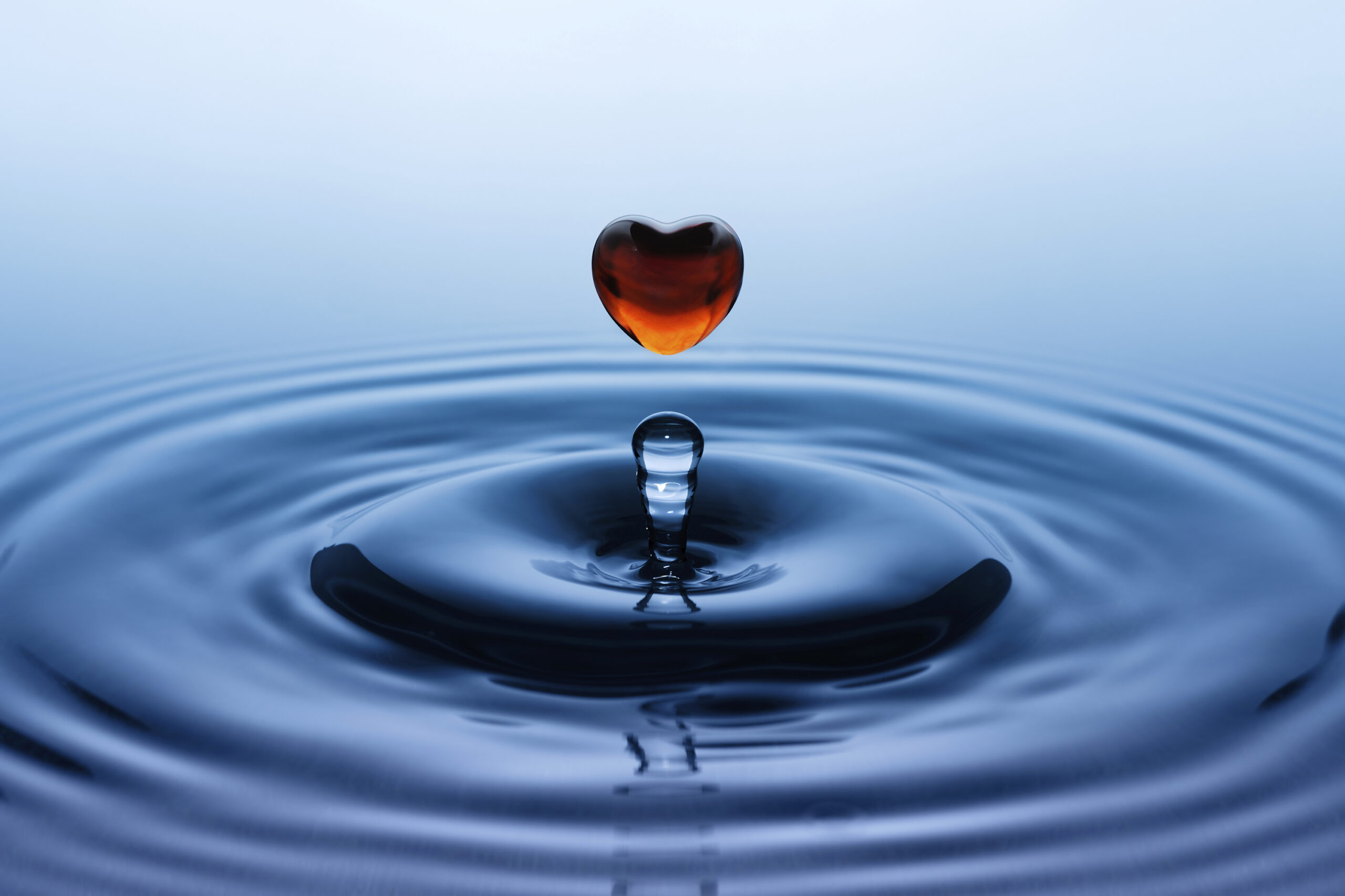 red glass heart in water making ripple